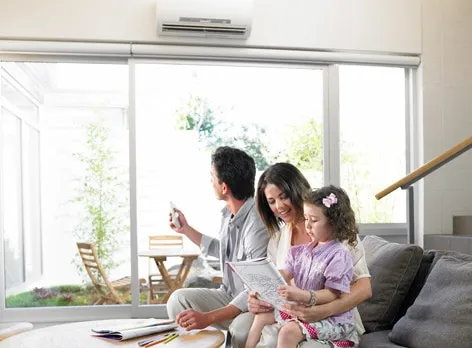family sitting in their living room with a ductless air system installed on the wall